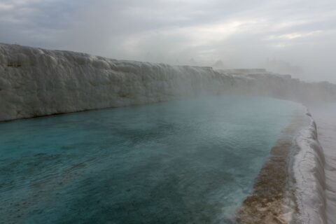 Misty morning at Pamukkale's thermal springs, showcasing natural beauty and calm waters.