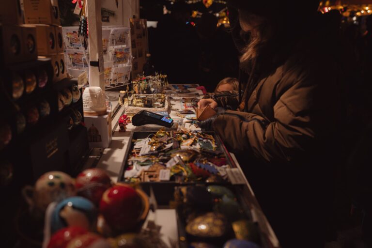 Warm and inviting evening market stall scene with people browsing souvenirs and handmade crafts.